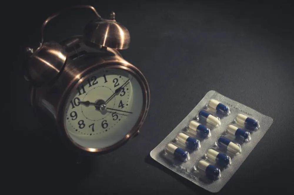 Alarm clock beside a blister pack of medication
